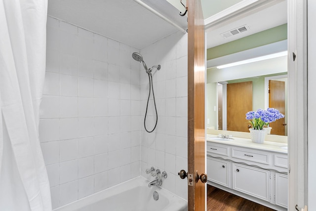 full bath featuring visible vents, double vanity, wood finished floors, a sink, and shower / bath combo
