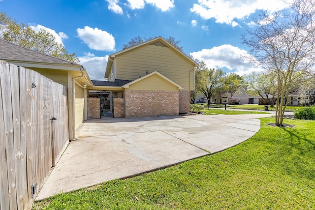 view of property exterior featuring brick siding, a lawn, roof with shingles, and driveway