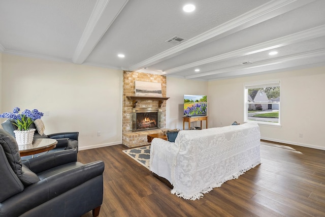 living area with a brick fireplace, baseboards, wood finished floors, beamed ceiling, and visible vents