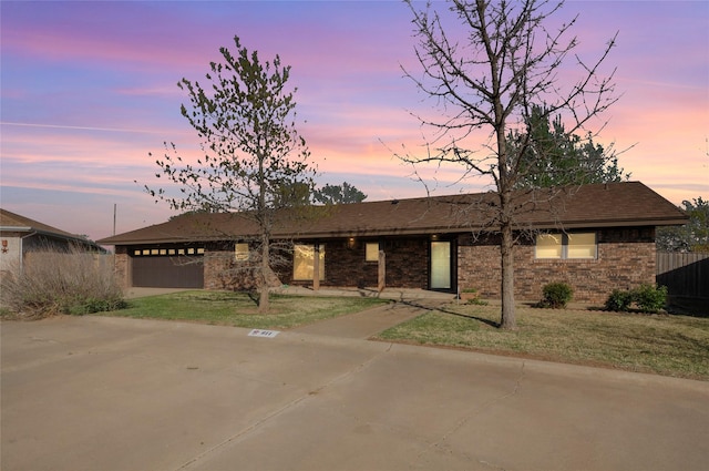 view of front of property with an attached garage, driveway, a front lawn, and brick siding