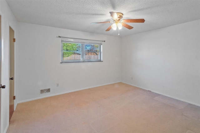 spare room featuring a textured ceiling, ceiling fan, light colored carpet, and visible vents