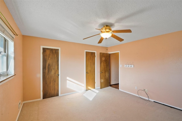 unfurnished bedroom featuring carpet floors, baseboards, a textured ceiling, and ceiling fan