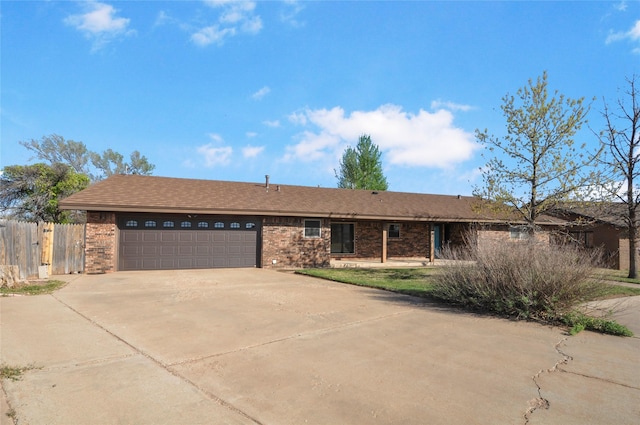 ranch-style home featuring concrete driveway, brick siding, fence, and a garage