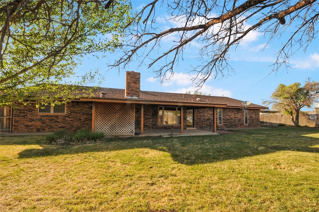rear view of house with fence, brick siding, a chimney, a patio area, and a yard