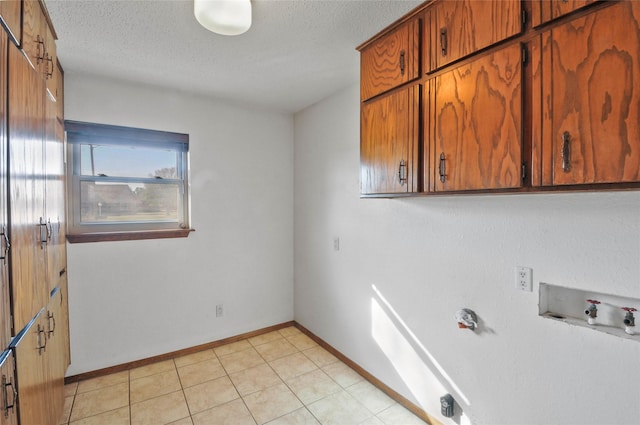 laundry area with cabinet space, a textured ceiling, baseboards, and hookup for a washing machine