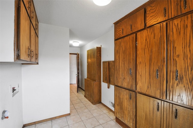 hallway with baseboards, a textured ceiling, a barn door, and light tile patterned floors