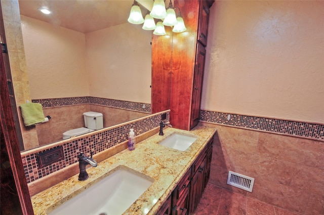 full bathroom featuring a sink, tile walls, a wainscoted wall, and visible vents