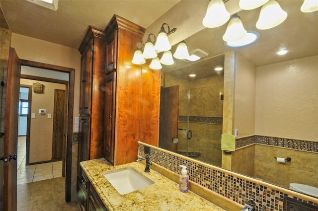bathroom with an inviting chandelier, vanity, tile walls, tile patterned floors, and a shower stall