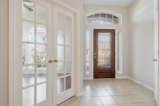 foyer entrance with french doors, baseboards, and light tile patterned flooring