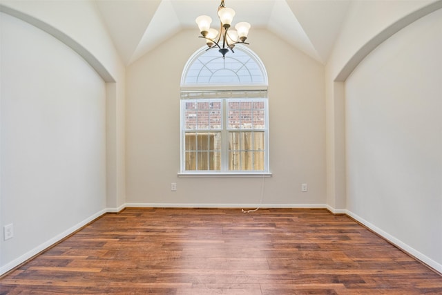 spare room featuring vaulted ceiling, wood finished floors, and a notable chandelier