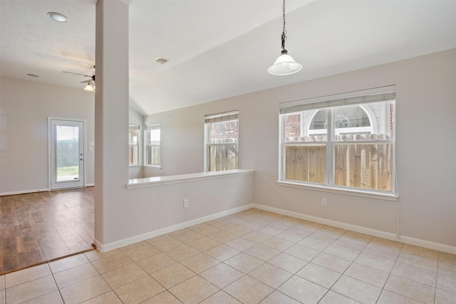 spare room featuring visible vents, baseboards, a ceiling fan, light tile patterned floors, and vaulted ceiling