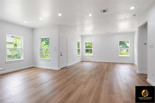 unfurnished living room with a healthy amount of sunlight, baseboards, light wood finished floors, and recessed lighting