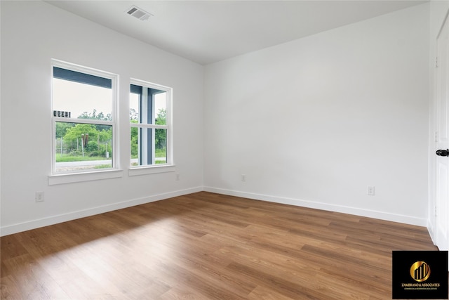 empty room featuring light wood-style floors, baseboards, and visible vents