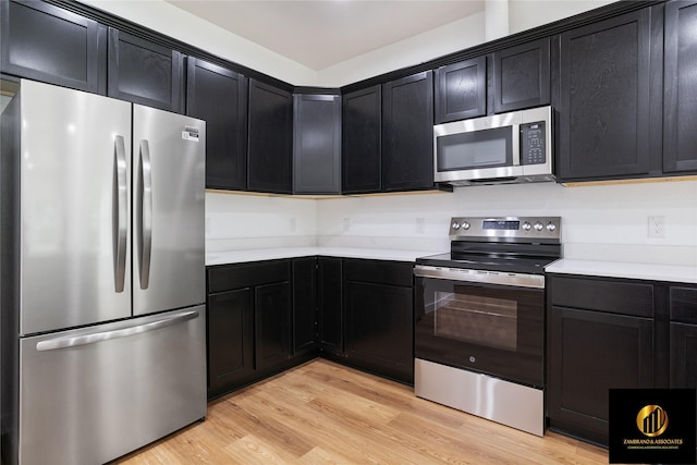 kitchen featuring dark cabinets, light countertops, appliances with stainless steel finishes, and light wood-type flooring