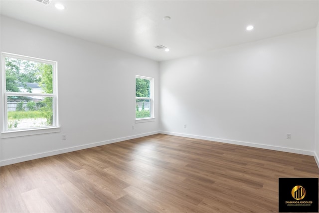 empty room featuring baseboards, plenty of natural light, light wood finished floors, and visible vents
