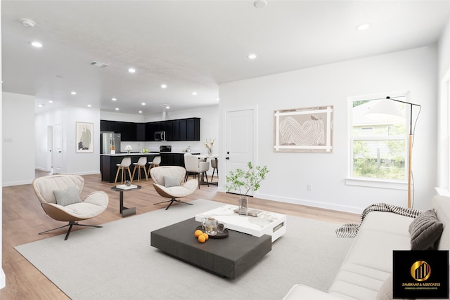 living area with baseboards, recessed lighting, light wood finished floors, and visible vents