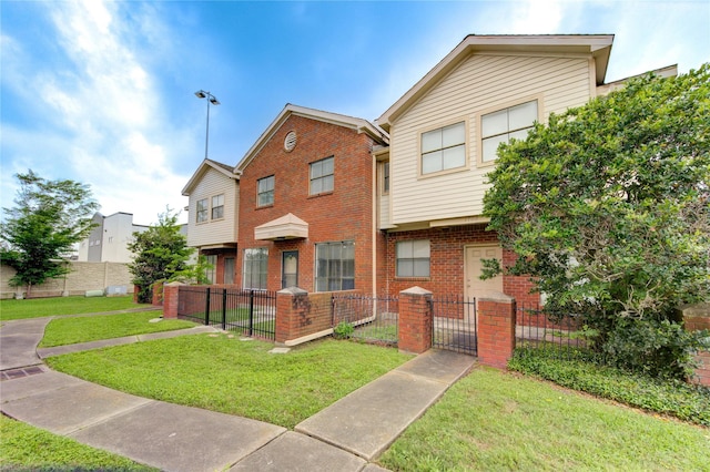 view of property with a gate, a fenced front yard, brick siding, and a front yard