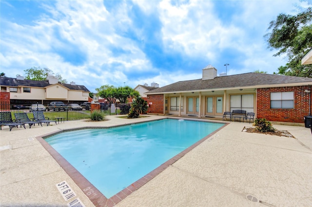 community pool with fence and a patio area