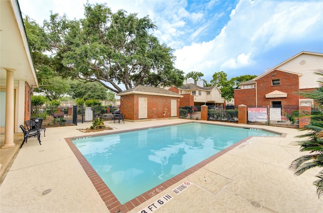 pool with fence, a patio, and a residential view