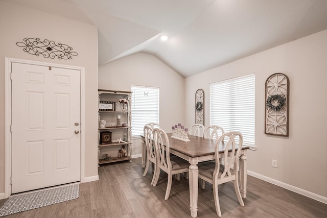 dining area featuring wood finished floors, baseboards, and lofted ceiling