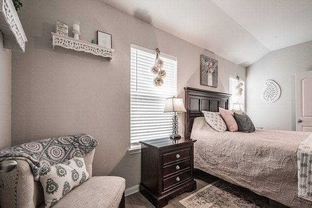 bedroom featuring dark wood-style flooring, baseboards, vaulted ceiling, and multiple windows