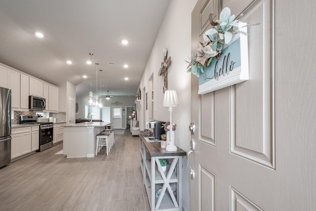 kitchen with decorative backsplash, a kitchen island with sink, a kitchen breakfast bar, appliances with stainless steel finishes, and open floor plan
