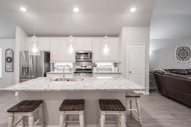 kitchen featuring baseboards, a breakfast bar area, a sink, appliances with stainless steel finishes, and backsplash