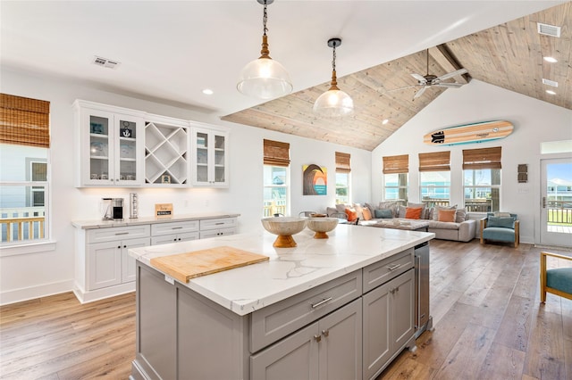 kitchen with gray cabinetry, a ceiling fan, a kitchen island, and light wood-type flooring