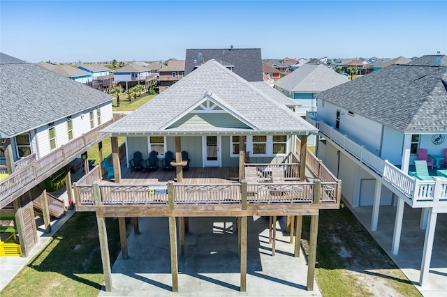 rear view of property with board and batten siding, roof with shingles, a deck, a residential view, and a carport