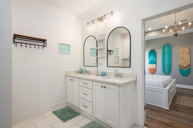bathroom with an inviting chandelier, a sink, baseboards, and double vanity