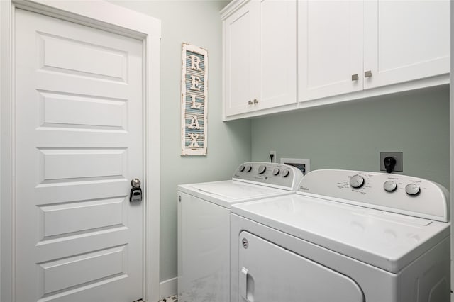 clothes washing area featuring cabinet space and washer and clothes dryer