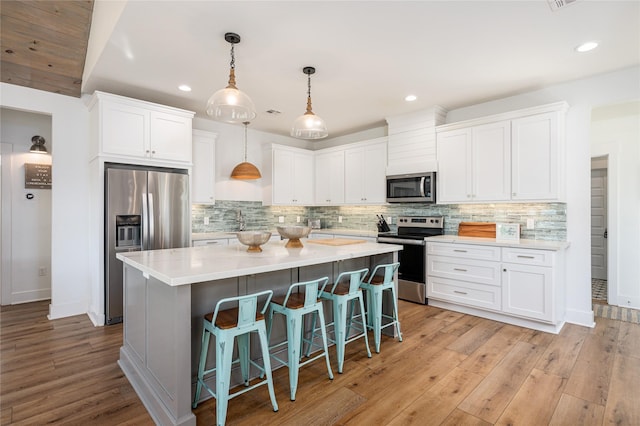 kitchen with a kitchen island, a breakfast bar, white cabinets, tasteful backsplash, and stainless steel appliances