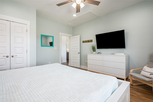 bedroom featuring a ceiling fan, attic access, wood finished floors, baseboards, and a closet