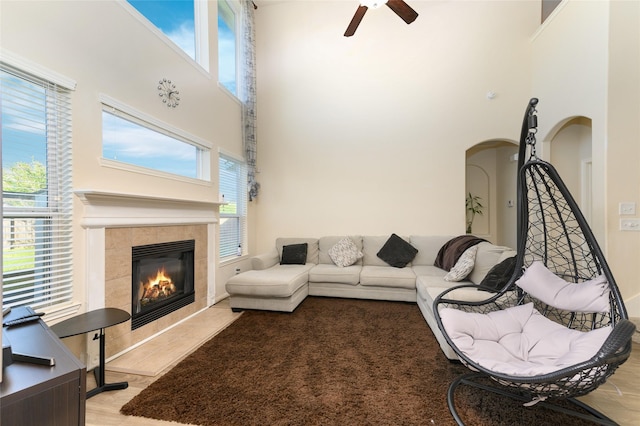 24618 Malca Manor Dr, Katy, TX 77493 - living room featuring a tiled fireplace, arched walkways, a high ceiling, and ceiling fan