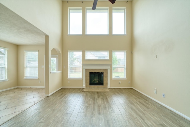 24618 Malca Manor Dr, Katy, TX 77493 - unfurnished living room with a ceiling fan, a tile fireplace, wood finished floors, baseboards, and a high ceiling