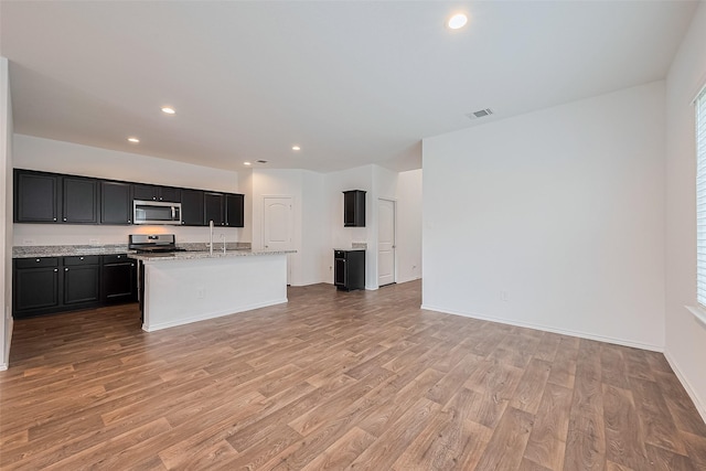12518 Pelican Bay Dr, Houston, TX 77038 - kitchen with dark cabinetry, stainless steel appliances, visible vents, and light wood-style floors