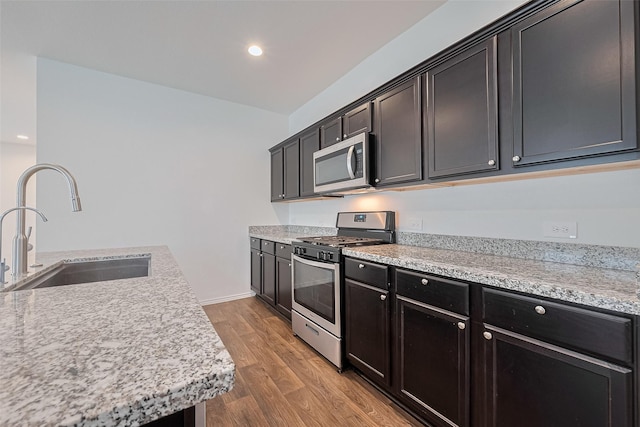 12518 Pelican Bay Dr, Houston, TX 77038 - kitchen featuring wood finished floors, baseboards, dark cabinetry, a sink, and appliances with stainless steel finishes