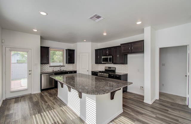 kitchen with backsplash, appliances with stainless steel finishes, visible vents, and a center island