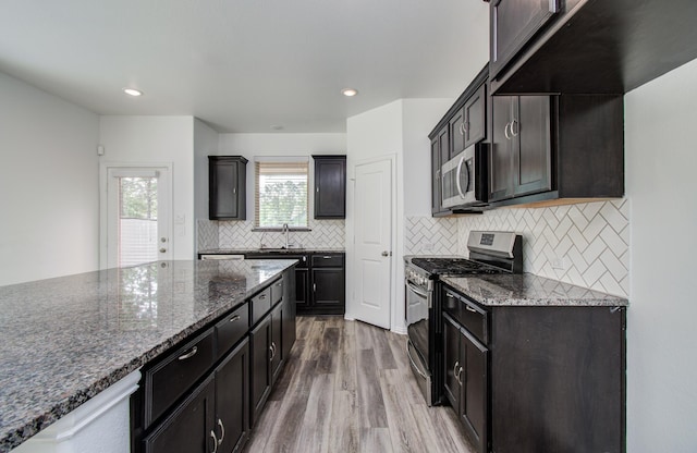 kitchen featuring a sink, dark stone counters, stainless steel appliances, and dark wood-type flooring