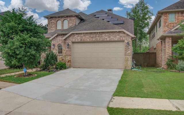 view of front of property with a shingled roof, an attached garage, brick siding, a front yard, and driveway