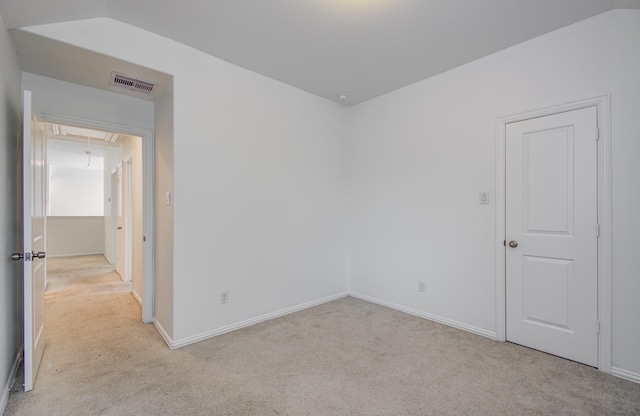 empty room featuring light colored carpet, attic access, baseboards, and visible vents