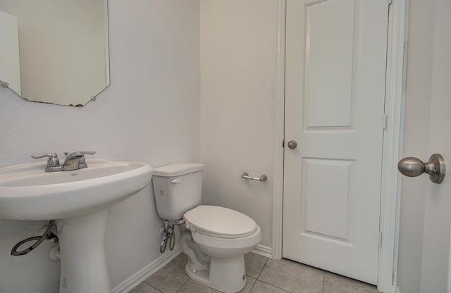 bathroom with baseboards, tile patterned floors, and toilet