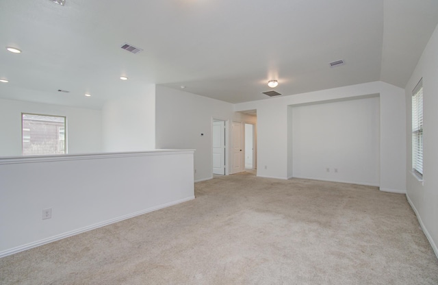 unfurnished room featuring visible vents, baseboards, and light colored carpet