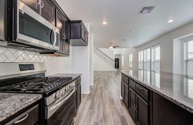 3730 Bach St, Iowa Colony, TX 77583 - kitchen featuring stainless steel appliances, backsplash, light wood-style floors, ceiling fan, and dark stone counters