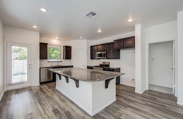 3730 Bach St, Iowa Colony, TX 77583 - kitchen with stainless steel appliances, dark brown cabinetry, dark wood-type flooring, a breakfast bar, and recessed lighting