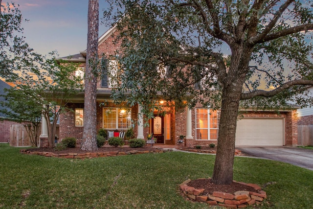 obstructed view of property featuring an attached garage, brick siding, driveway, and a front yard