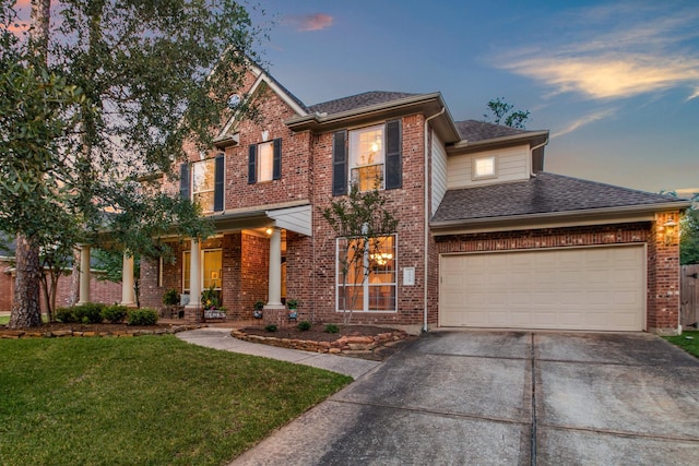 view of front of home featuring brick siding, roof with shingles, a front yard, and concrete driveway