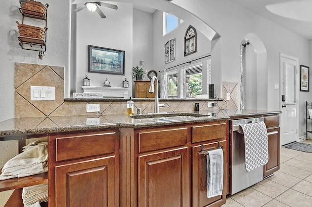 kitchen with stainless steel dishwasher, arched walkways, plenty of natural light, and a sink