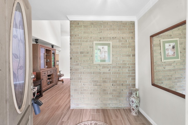 bathroom with crown molding, baseboards, wood finished floors, and brick wall