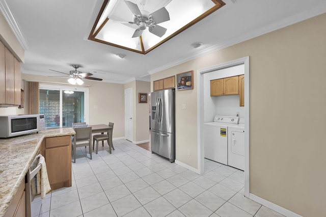 kitchen with appliances with stainless steel finishes, light tile patterned floors, ceiling fan, and washing machine and clothes dryer